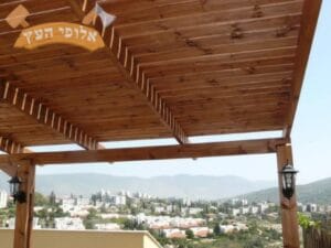 פרגולה מעץ במרפסת דירה בצפון עם לכה לשימור העץ