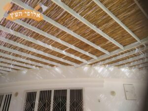 פרגולה מעץ אשוח צבוע בלבן עם הצללה עם במבוק וסנטף בבית פרטי בשכונת בנה ביתך באופקים